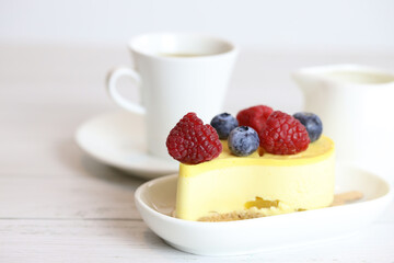 light cake with raspberries and blueberries and a cup of coffee, pleasant light breakfast