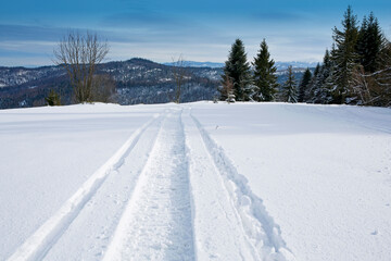 fresh snowmobile trail in the snow on a mountain slope