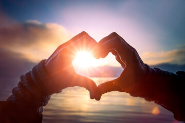 Fototapeta na wymiar Herz aus Händen mit Sonnenlicht am See