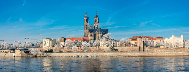 Panoramic view over Magdeburg historical downtown in Winter with icy trees and blue sky at sunny...