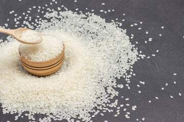 White round rice in wooden bowl. Wooden spoon with rice. Rice is scattered on table