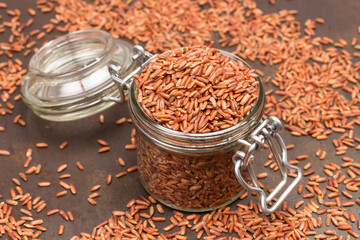 Brown rice in glass jar. Rice is scattered on table