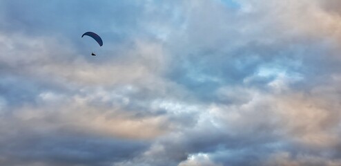 Paraglider ao a misty day over a dramatic sky