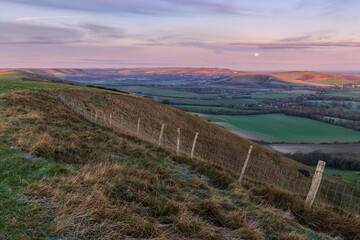 The full moon setting over the Lewes Downs in the north west.  From Firle Beacon on the South Downs...