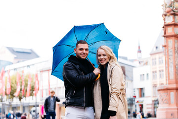 Young couple on a date walks under an umbrella through the market square in Mainz, Germany