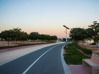 Jogging and cycling tracks in Al Warqa park, Dubai, UAE in the evening. Lamp post powered by solar panels can be seen in the picture. Outdoors - obrazy, fototapety, plakaty