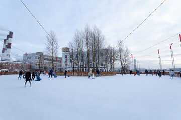 Outdoor ice rink with people skating at the daytime.