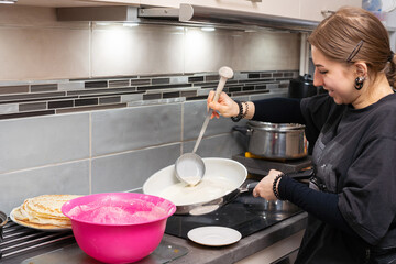 A teenage girl pours the pancake batter into a hot pan with a large spoon. Liquid pancake batter. Homemade pancakes.