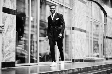 Portrait of young and handsome african american businessman in suit and white sneakers.