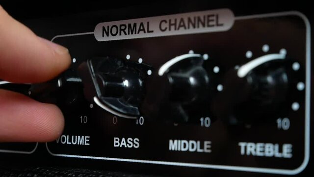 Close-up of a hand turning the bass and volume on the amplifier