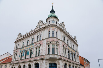 Neo-Renaissance white building of the former Farmers' bank Podripska with red sgraffito mural decorated plaster in Roudnice nad Labem in winter day, Central Bohemia, Czech Republic
