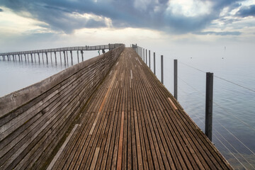 Stunning foggy view of the pedestrian wooden bridge (Holzsteg) crossing the Zurich Lake at its narrowest point between Hurden (Seedam) and Rapperswil, Switzerland