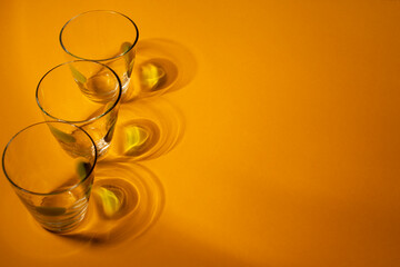 Glasses with strong shadows on yellow background. Food concept.