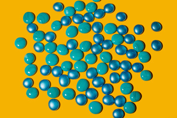 Blue and turquoise glass pebbles on a yellow background.