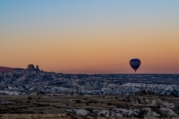 Hot air balloon rising in Cappadocia, Uchisar castle and city in