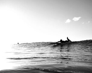Surf minimalism - Overexposed surfer paddles for a wave