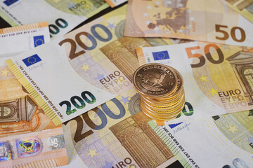  stack of gold coins lie on spread out euro banknotes