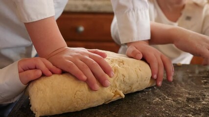 Hands of the kids are kneading pretzel dough. Camera focuses on the little kids’ hands as the knead the dough. - Powered by Adobe