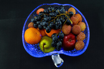 Still life in a crystal plate with blue illumination on a black background with a top view