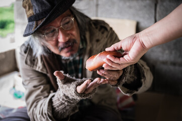 Homeless senior man with gray beard sitting hungry and beggar from people walking street.