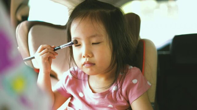 Asian toddler girl try to wearing make up using the mother brush, paint her face and showoff, child activity, little make up artist, kid beauty blogger 