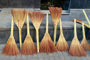 Sale of straw household brooms on the Yerevan street in Armenia in summer outdoors