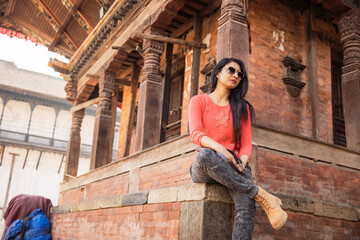 Pretty young women relaxing at Durbar Square temple, Nepal.