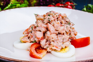 Lobster salad with egg and tomato on white plate.