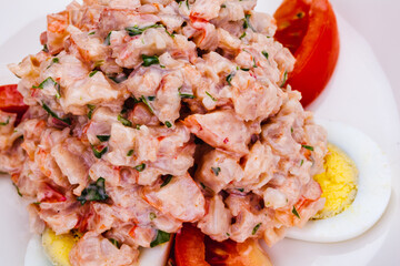 Lobster salad with egg and tomato on white plate.