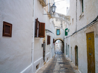 Fototapeta na wymiar Picturesque cobblestone alley with traditional white houses in the ancient town of Ostuni, Apulia region, southern Italy 