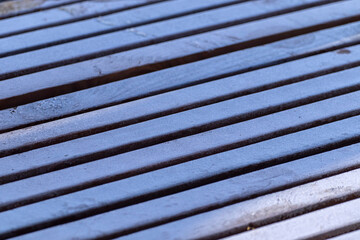 Wooden bench covered with hoarfrost, close up. Focus in the center, blurred edges.