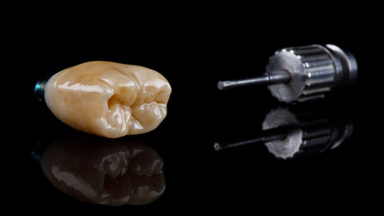 composition dental crown and orthopedic screwdriver on black glass with reflection