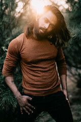 Fototapeta premium Long hair bearded young man posing in outdoor with tree background.