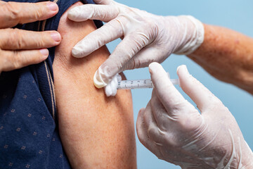 Vacinação. Detalhe de mãos com luvas de pessoa a vacinar outra pessoa.