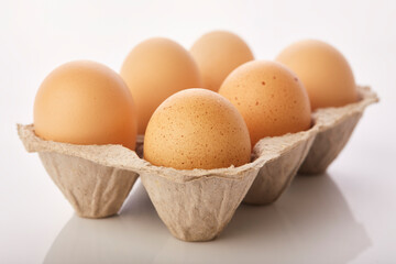 Brown eggs in egg box on white background.
