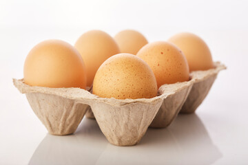 Brown eggs in egg box on white background.