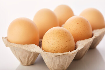 Brown eggs in egg box on white background.