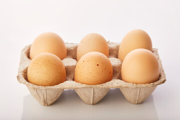 Brown eggs in egg box on white background.