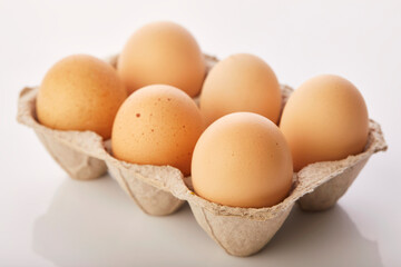 Brown eggs in egg box on white background.