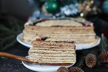 Butter honey layered cake on a dark background with fir branches and decorations in the background. Food Christmas background.