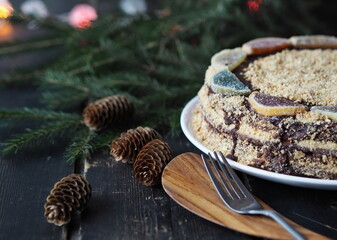Butter honey layered cake on a dark background with fir branches and decorations in the background. Food Christmas background.
