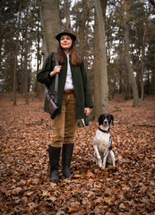 Jagd und Wildhege - junge Jägerin mit ihrem Hund im Jagdrevier, jagdliches Symbolfoto.