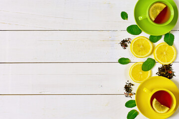Background of multicolored cups of tea, lemon and mint on a white wooden background.