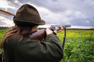 Jagd und Wildhege, junge Jägerin zielt mit einem Gewehr auf flüchtiges Wild - jagdliches...