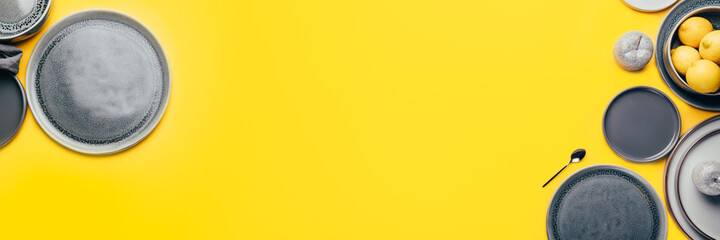 Different gray empty ceramic plates on yellow background, trendy colors 2021, banner size, Top View, Copy Space