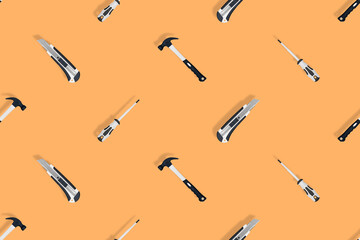 Tools seamless pattern. Tools: hammer, screwdriver and knife on an orange background.