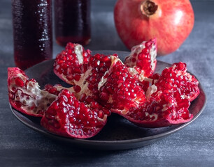 Ripe pomegranate cut into pieces and freshly squeezed pomegranate juice in two bottles. The drink is good for your health.
