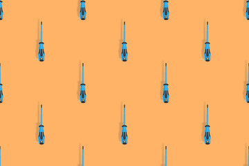 Screwdrivers seamless pattern. Metal screwdrivers with a rubberized handle on an orange background.