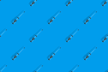 Screwdrivers seamless pattern. Metal screwdrivers with a rubberized handle on a blue background.