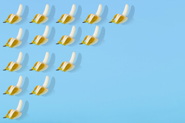 Trendy Summer pattern made with open fresh banana fruit on bright light blue background.
